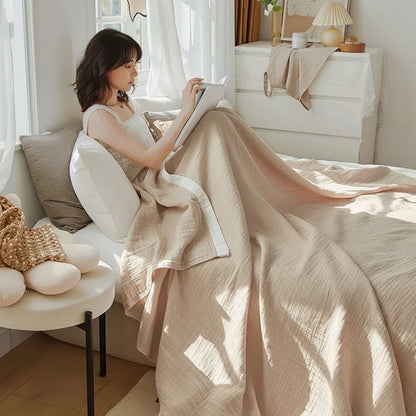 Drap en gaze de coton beige avec une femme qui lit dans son lit