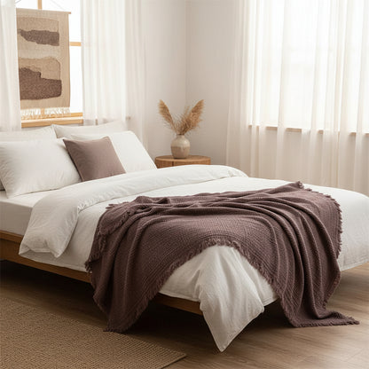 Couverture en coton boho de couleur prune sur un lit